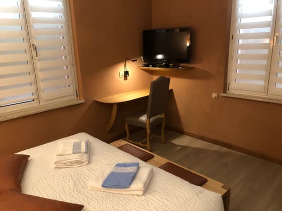 Coin bureau d'une chambre : plan de travail en bois fixé au mur, téléviseur et placard intégré.